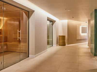 Modern hotel corridor with glass doors leading to a sauna and ambient lighting.