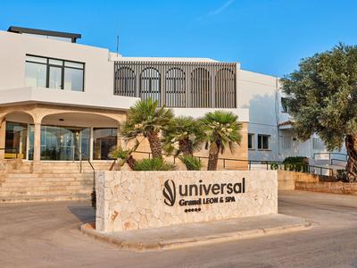 Modern hotel building with palms and clear sky, Universal brand sign in front.