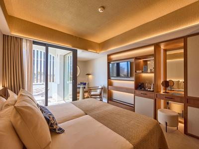 Bright hotel room with twin beds, large window, and modern wooden furnishings.