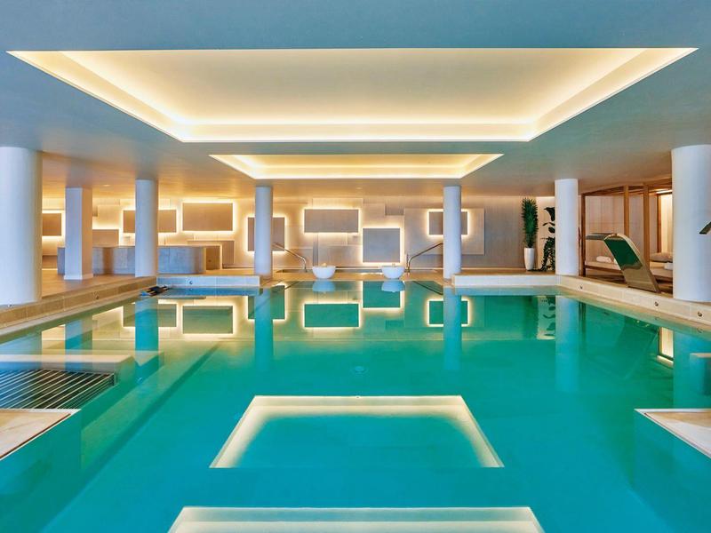 Spacious indoor pool with modern lighting and seating in a luxury hotel.