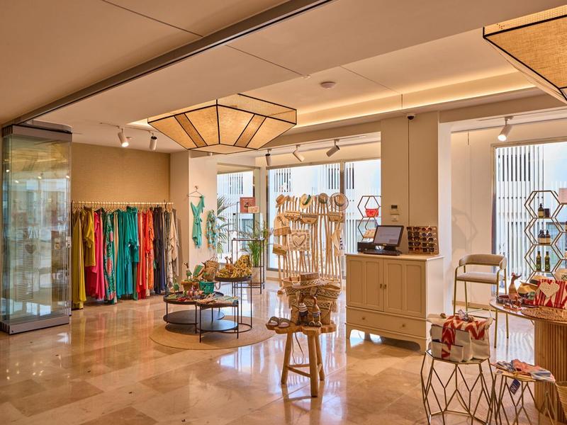 Bright, elegant boutique with colorful clothes, wooden furniture, and large windows.
