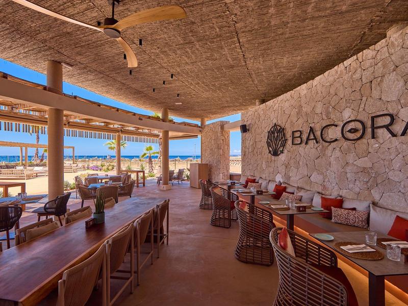 Open-air restaurant with wooden furniture and sea view at Bacora hotel.