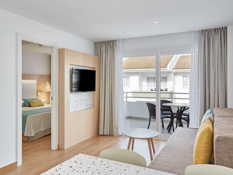 Soggiorno moderno in camera d'albergo con divano, balcone e camera adiacente.