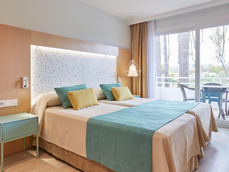 Camera d'hotel moderna con letto matrimoniale, illuminazione accogliente e balcone con area salotto.