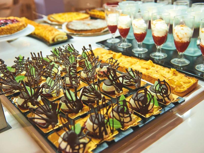 Różnorodne, eleganckie desery ustawione na bufecie.