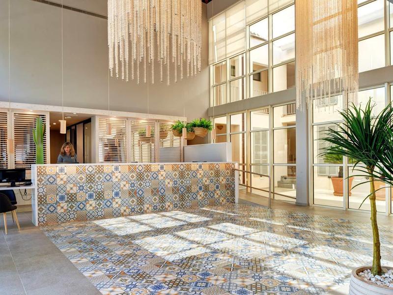 Jasna recepcja hotelowa z kolorowymi kafelkami i dużymi oknami.