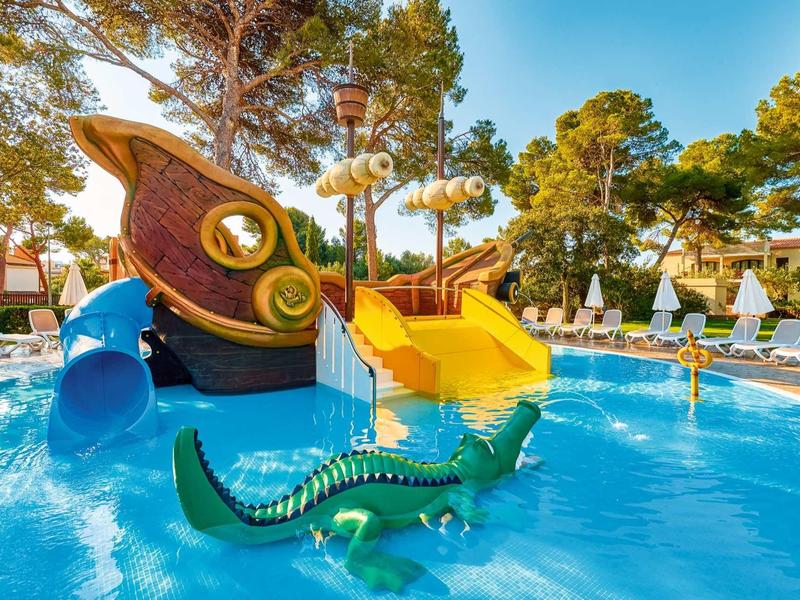 Basen z kolorowymi zjeżdżalniami i konstrukcją w kształcie łodzi.