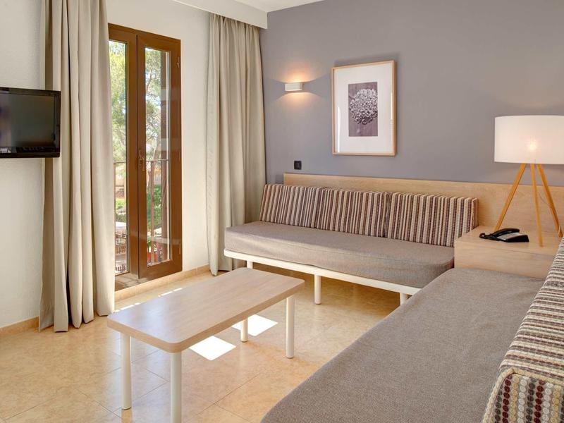 Salon z kanapami, stolikiem, telewizorem i drzwiami balkonowymi.