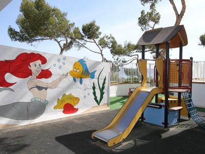 Plac zabaw dla dzieci ze zjeżdżalnią przed ścianą z kolorowymi morskimi malunkami.