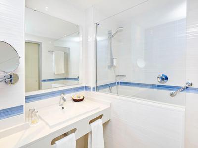 Nowoczesna łazienka hotelowa z dużą wanną, lustrem i umywalką z ręcznikami.