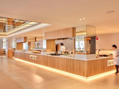 Nowoczesna, jasna recepcja hotelowa z drewnianą okładziną i personelem.