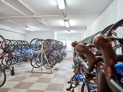 Wnętrze z wieloma rowerami zawieszonymi na ścianie w jasnym garażu lub pomieszczeniu do przechowywania rowerów.