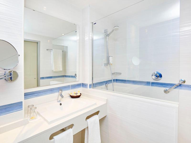 Nowoczesna łazienka hotelowa z dużą wanną, lustrem i umywalką z ręcznikami.