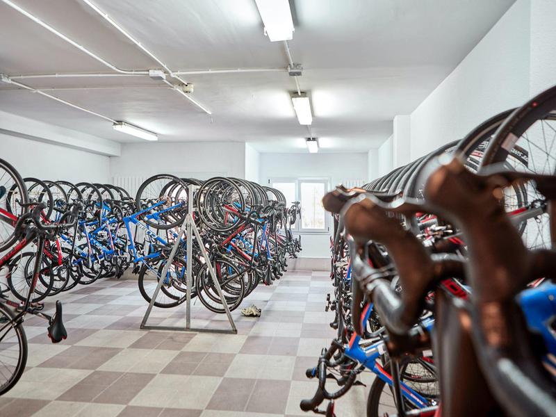 Pomieszczenie na rowery z wieloma rowerami szosowymi w jasnej, dobrze oświetlonej sali.
