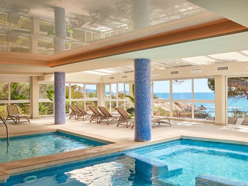 Basen kryty z miejscami do siedzenia i panoramicznymi oknami z widokiem na morze.