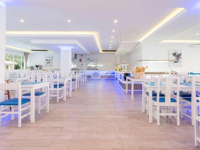 Restaurant moderne avec des chaises blanches et des coussins bleus dans un espace lumineux et ouvert.