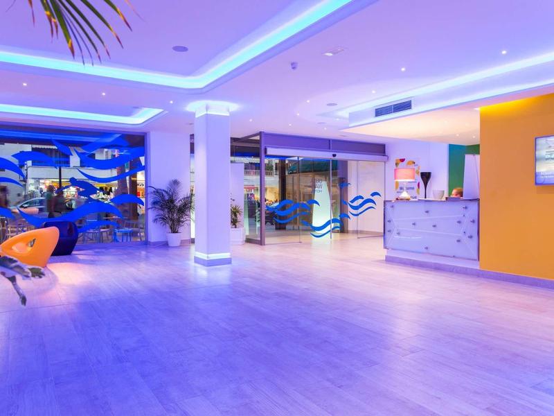 Moderner Empfangsbereich mit heller Holzoptik, blauem LED-Licht und orangen Akzenten.