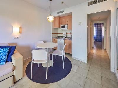 Stanza luminosa con angolo cottura, piccolo angolo pranzo e corridoio con porte