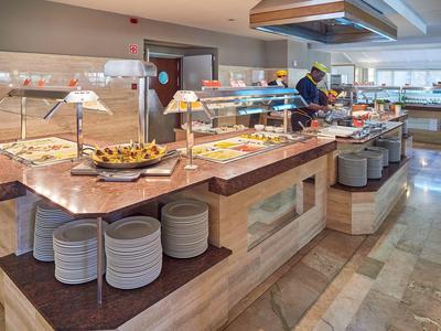 Postazione buffet con vari piatti e piatti in una luminosa sala per la colazione.