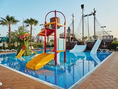 Area giochi acquatica colorata con scivoli e nave pirata nella piscina dell'hotel.