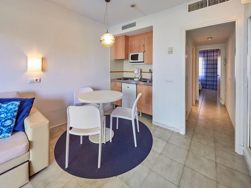 Stanza luminosa con angolo cottura, piccolo angolo pranzo e corridoio con porte