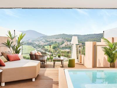 Dachterrasse mit Pool, Lounge-Möbeln und Blick auf grüne Hügel.