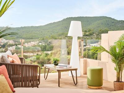 Terrasse mit moderner Sitzgruppe, Pflanzen und Bergblick bei klarem Himmel.