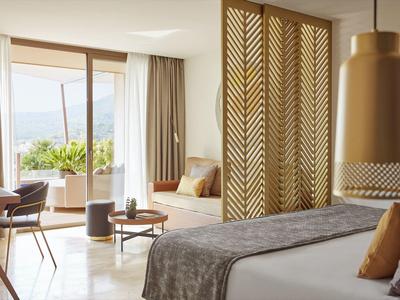 Helles Hotelzimmer mit Doppelbett, Akzentwand, Sitzbereich und Balkon mit Blick ins Grüne.