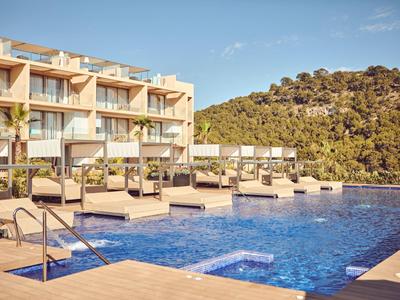 Moderner Außenpoolbereich mit Liegestühlen vor einem Hotel und Hügel im Hintergrund