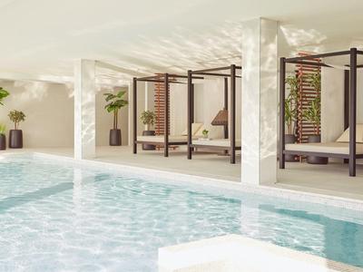 Innenpool mit flachen Liegen und Pflanzen in einem modernen Spa-Bereich.