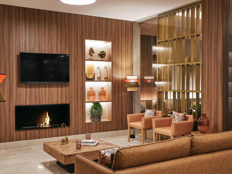 Modern eingerichteter Hotel-Loungebereich mit Kamin, gemütlichen Sesseln und Holzwänden.