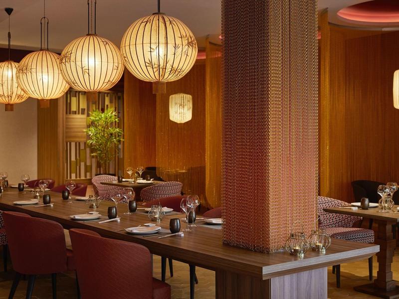 Modernes Restaurant mit warmen Holztönen und runden Hängelampen, gemütliche Sitzbereiche.