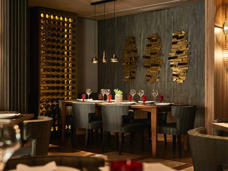 Elegantes Restaurant mit Holzwänden, modernem Weinregal und stilvoll gedeckten Tischen.