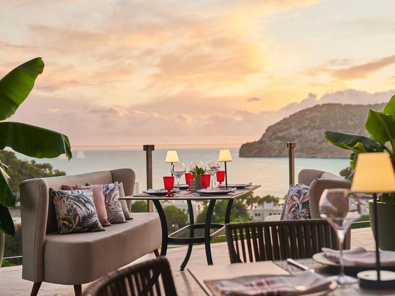 Gemütliche Terrasse mit Sofas und Tisch, Blick auf Meer und Sonnenuntergang.