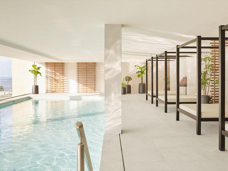 Moderner Innenpoolbereich mit Liegen und großen Fenstern in einem Hotel.