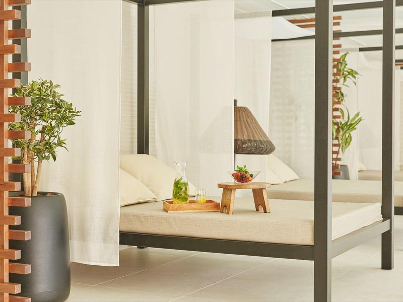 Minimalistisches Schlafzimmer mit schwarzen Metallrahmen, weißen Vorhängen und hölzernem Beistelltisch.