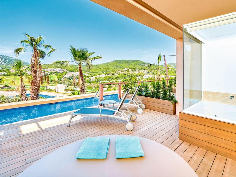 Terrasse mit Pool, Palmen und Blick auf grüne Hügel unter blauem Himmel.