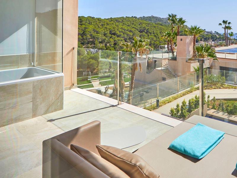 Moderne Hotelterrasse mit Liegestühlen, Pool und Blick auf bewaldete Hügel.