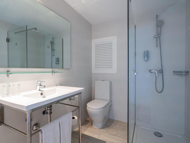 Baño moderno y limpio con lavabo, inodoro y ducha en tonos neutros.