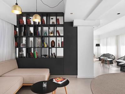 Moderner Wohnraum mit beige Sofa, schwarzem Bücherregal und Couchtischen in warmem, neutralem Ambiente