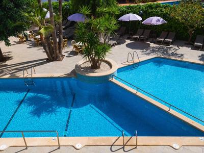 Dwa połączone niebieskie baseny z palmami i parasolami po bokach.