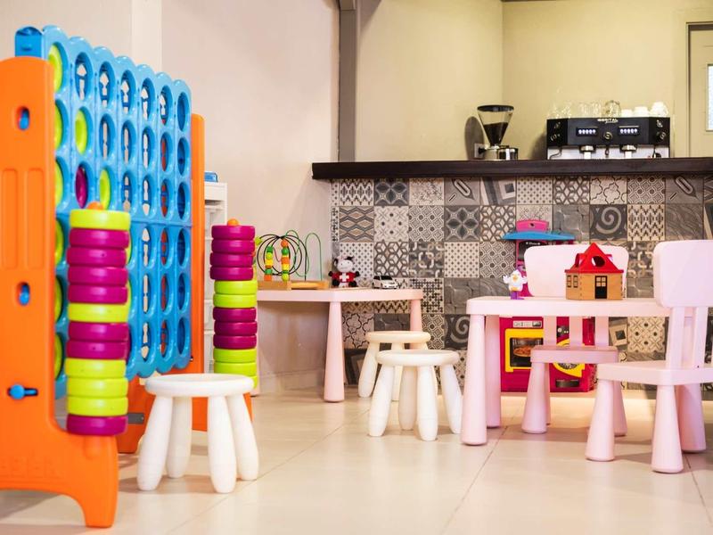 Espace de jeux pour enfants avec jeu de chevilles coloré et petites tables et chaises dans une pièce lumineuse.