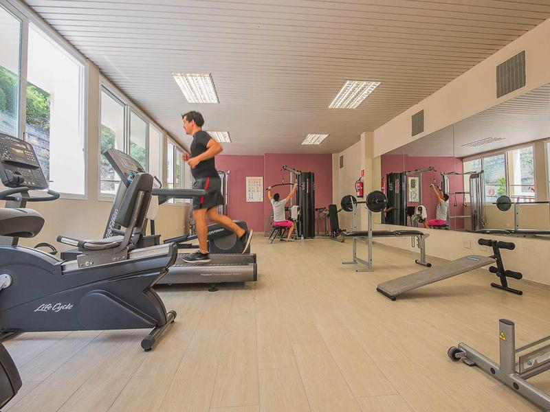 Salle de sport lumineuse avec tapis roulants, appareils de fitness et un homme en train de s'entraîner.