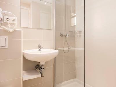 Nowoczesna łazienka z kabiną prysznicową, umywalką i toaletą w neutralnych kolorach.