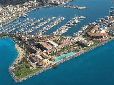 Widok z lotu ptaka na marinę z hotelami, przystaniami jachtowymi i długim basenem nad morzem.