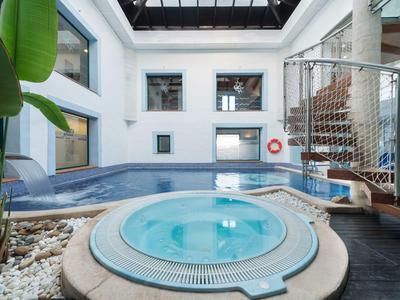 Moderner Innenbereich mit Whirlpool und Schwimmbecken unter einem Glasdach.