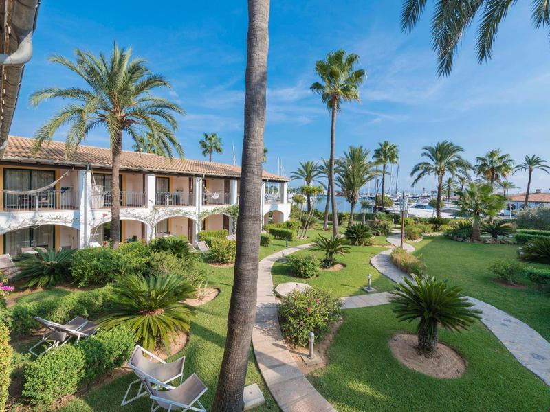 Kompleks hotelowy z budynkami o dwóch do trzech pięter, palmami i zadbanym ogrodem pod czystym niebem