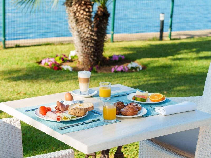 Stół na śniadanie na świeżym powietrzu z sokiem pomarańczowym, rogalikami i wędlinami nad jeziorem.