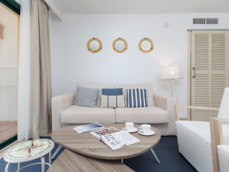 Nowoczesny salon z kanapą, okrągłym stołem i stylową dekoracją ścienną w pokoju hotelowym.