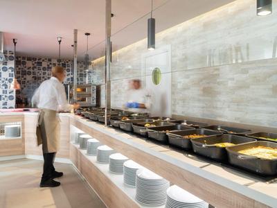 Buffetbereich mit warmen Speisen und einem Koch in einer modernen Hotelküche.